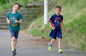 Two children running on a park alley